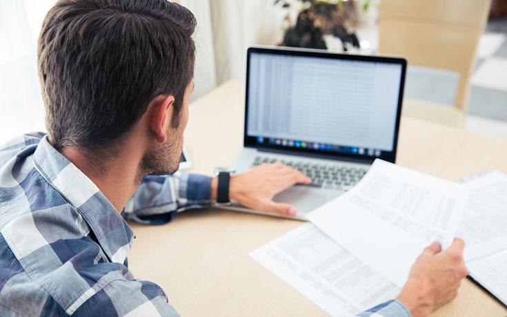 Man at laptop with financial papers filling out mortgage application